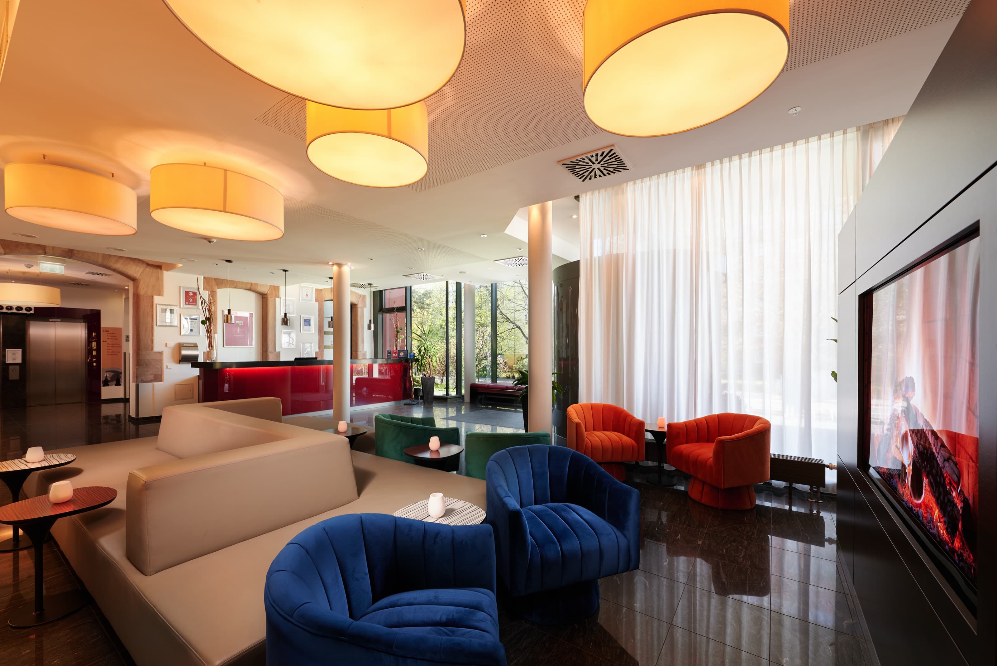 Gemütlicher Barbereich im NOVINA Hotel Tillypark mit farbigen Loungesesseln und stimmungsvoller Beleuchtung am Abend