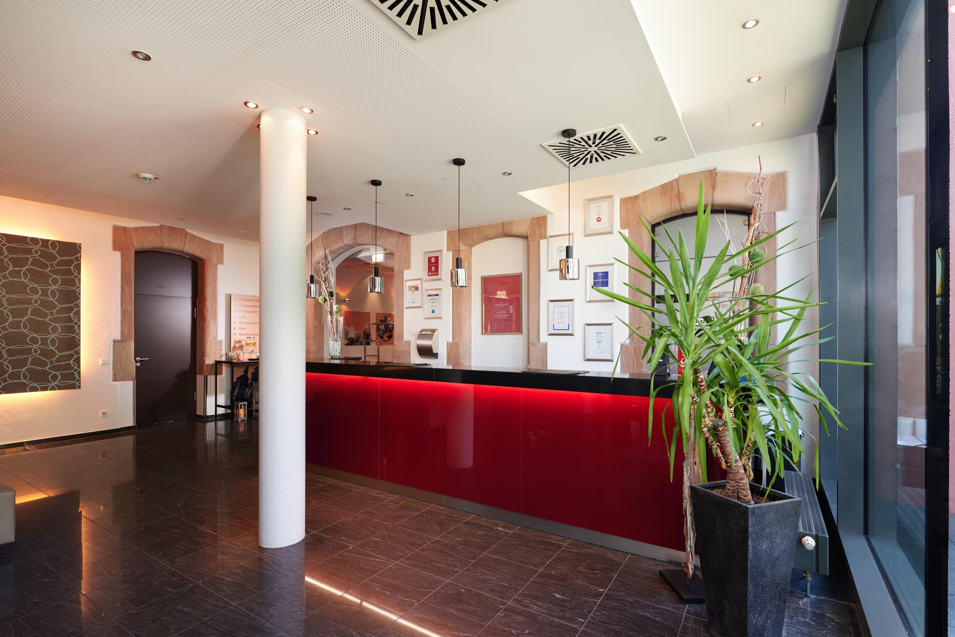 Einladender Empfangsbereich im NOVINA Hotel Tillypark Nürnberg mit warmer Beleuchtung und begrünter Sitzecke